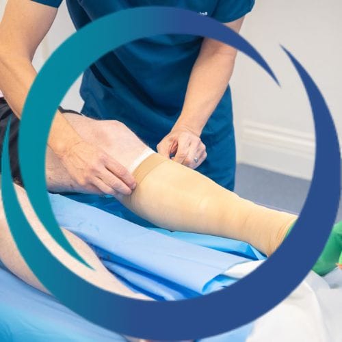 A nurse applying compression stockings to a patient post varicose vein surgery.